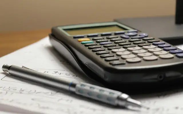 A calculator and a pen on a sheet of handwritten figures