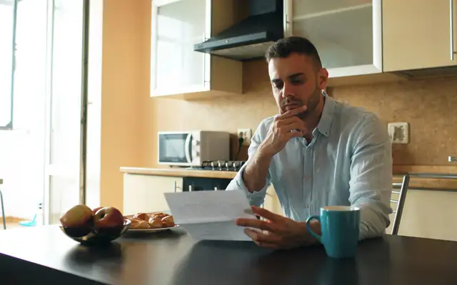 A man reading a document at his kitchen table