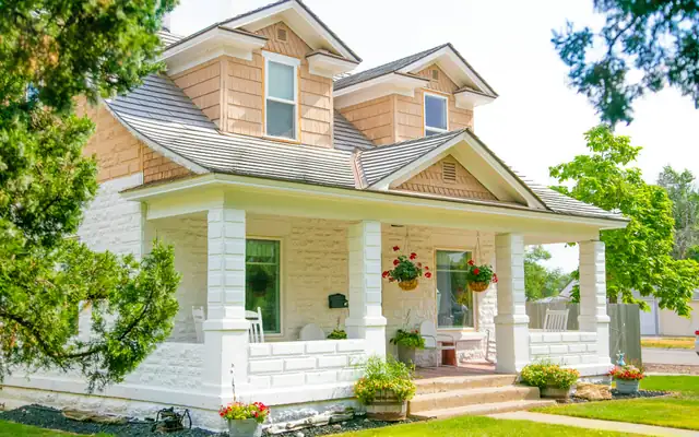 A white house with a deep front porch, flower boxes and a green lawn