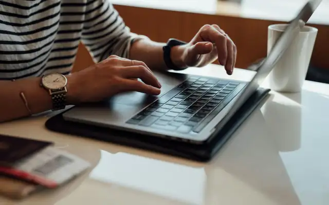 Hands typing on a laptop at a table