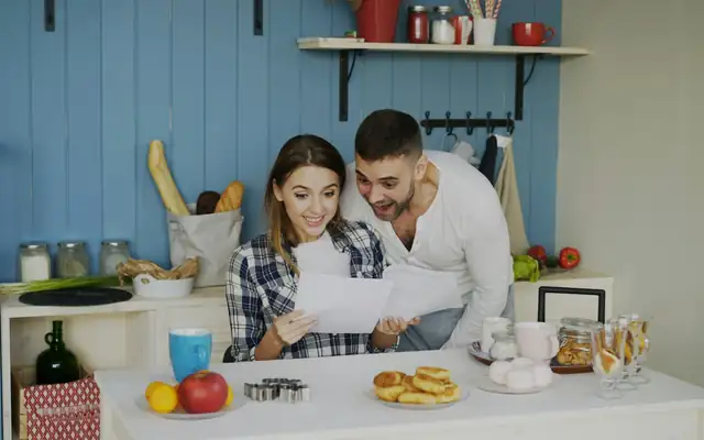 A couple reading papers together in a bright kitchen