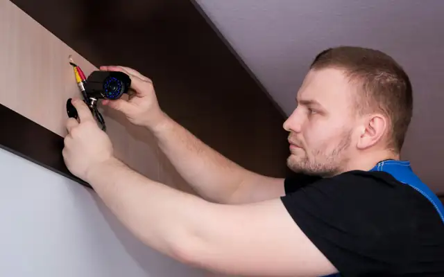 A man fixing something on a wall with a screwdriver